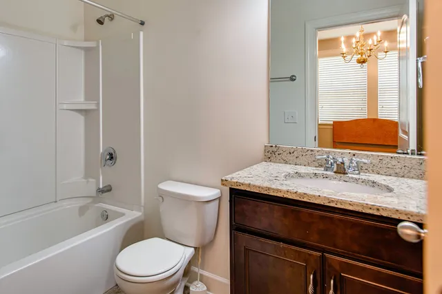 a bathroom with a granite countertop toilet sink and mirror