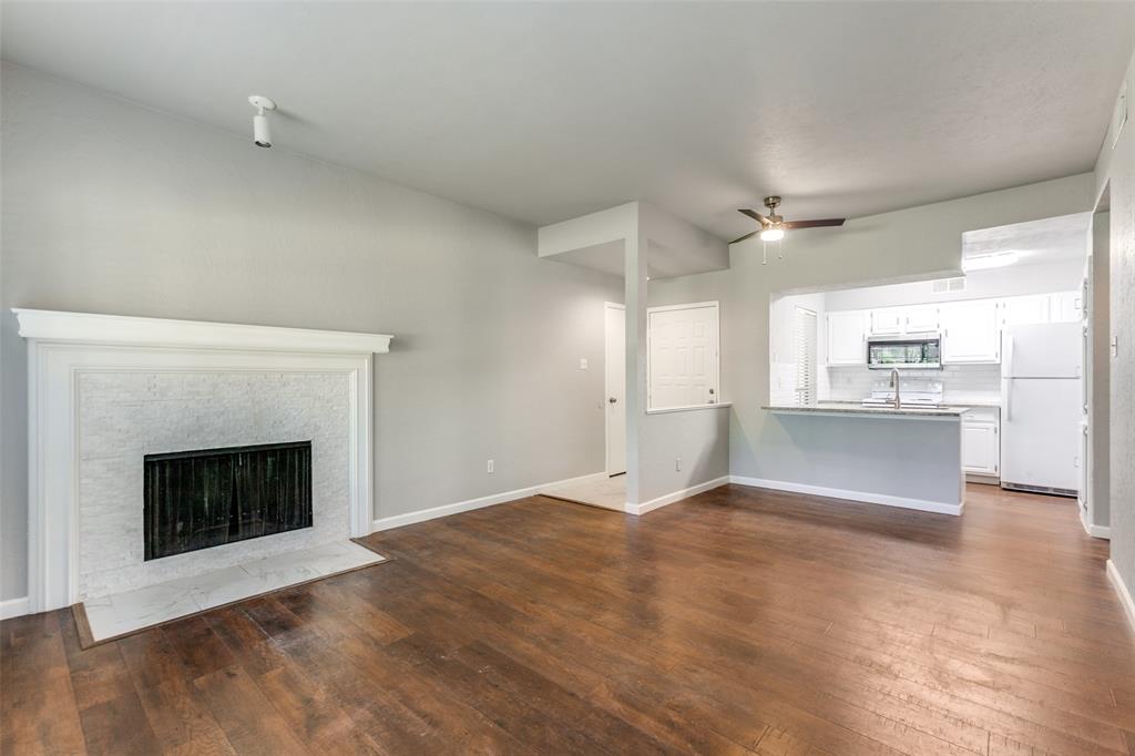 a view of kitchen and empty room with wooden floor