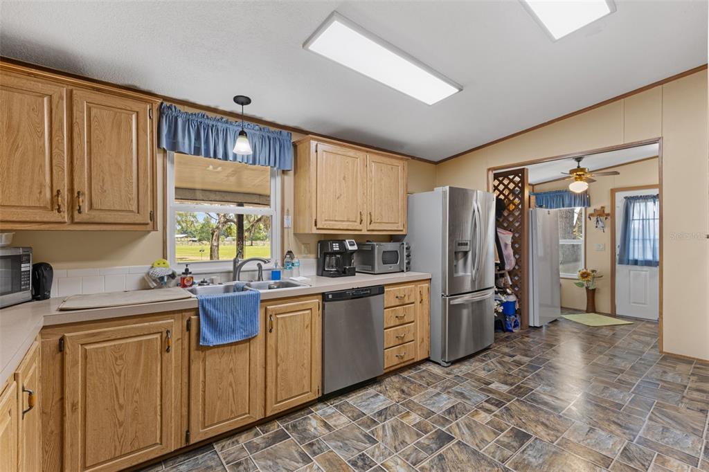 6689 Southeast 55th Street Trenton, FL 32693 - Photo 8 of 83 a kitchen with stainless steel appliances granite countertop a refrigerator a sink dishwasher a stove with wooden cabinets and floor