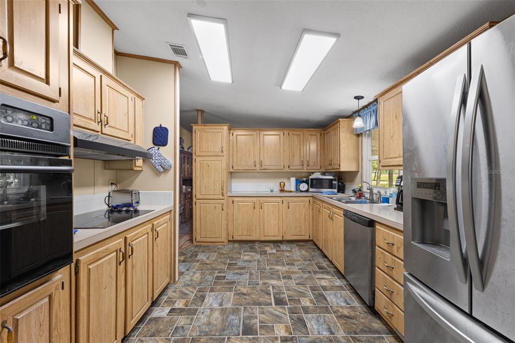 6689 Southeast 55th Street Trenton, FL 32693 - Photo 9 of 83 a kitchen with stainless steel appliances granite countertop a refrigerator a stove and a sink