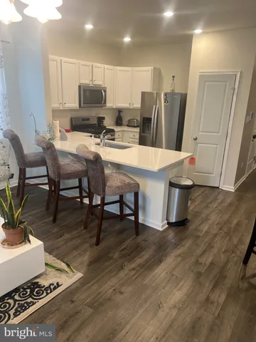 a living room with stainless steel appliances furniture a rug and a view of kitchen