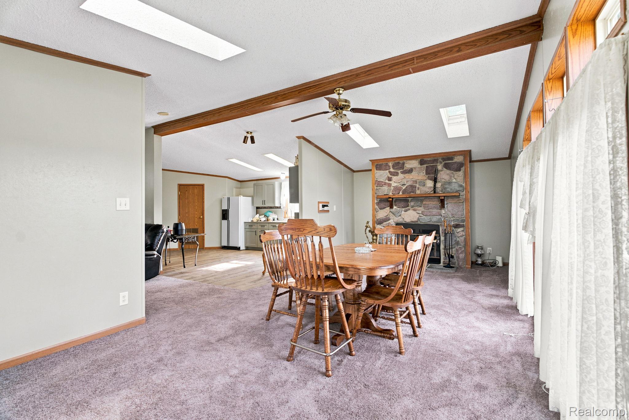 2390 Lakeshore Road Applegate, MI 48401 - Photo 55 of 97 Stone-faced fireplace with a wood mantle, vaulted ceiling with exposed wood beams, and a ceiling fan