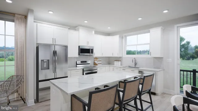 a kitchen with stainless steel appliances a table chairs refrigerator and microwave