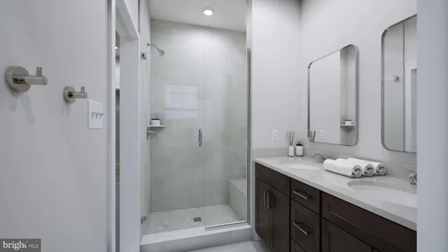 a bathroom with a granite countertop sink two mirror and shower