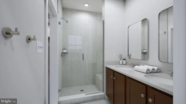 a bathroom with a granite countertop sink two mirror and shower