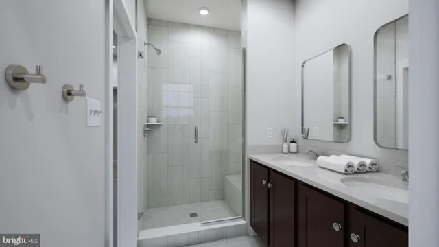 a bathroom with a granite countertop sink two mirror and shower