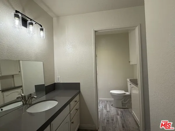 a bathroom with a granite countertop sink toilet a mirror and shower