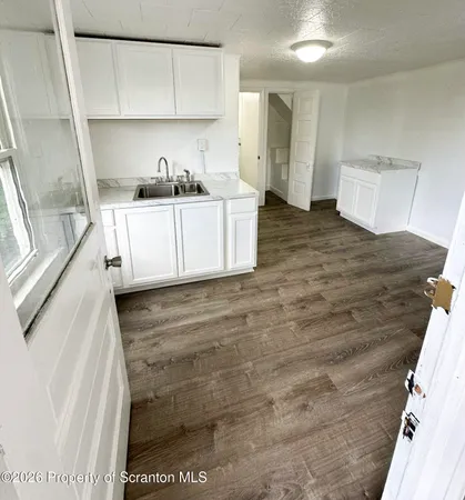 a view of a kitchen with wooden floor and a sink