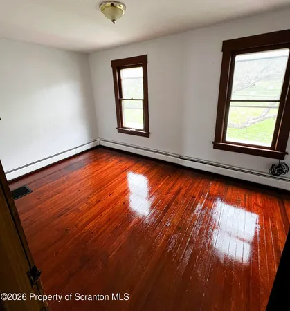 a view of lot of an empty room with wooden floor and a window