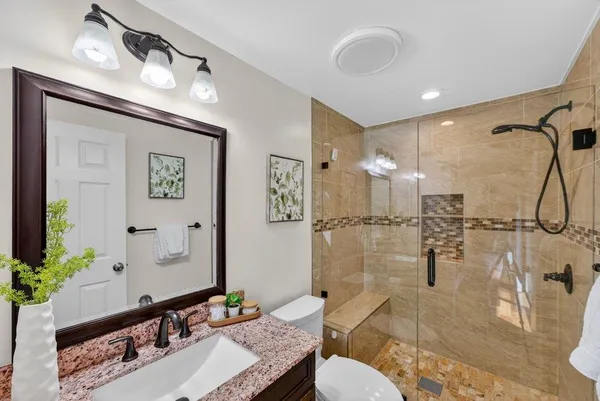 a bathroom with a granite countertop sink a mirror and a shower