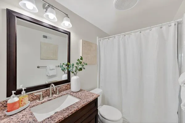 a bathroom with a granite countertop sink and a mirror with toilet