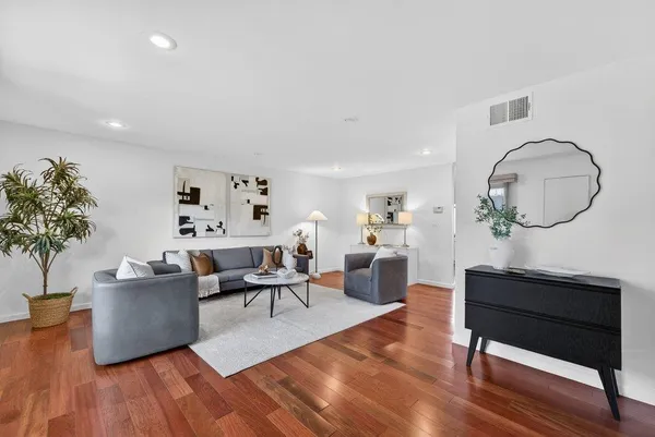 a living room with furniture a potted plant and a wooden floor