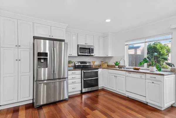 a kitchen with granite countertop white cabinets and stainless steel appliances