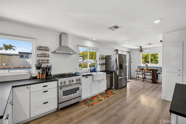 a large white kitchen with stainless steel appliances lots of counter space and wooden floor