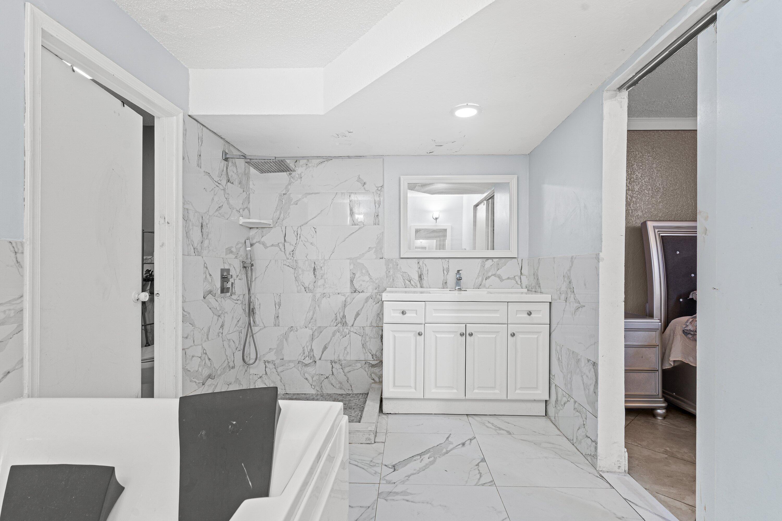 4134 Northwest 2nd Lane Delray Beach, FL 33445 - Photo 20 of 28 a spacious bathroom with a granite countertop sink a mirror and a bathtub