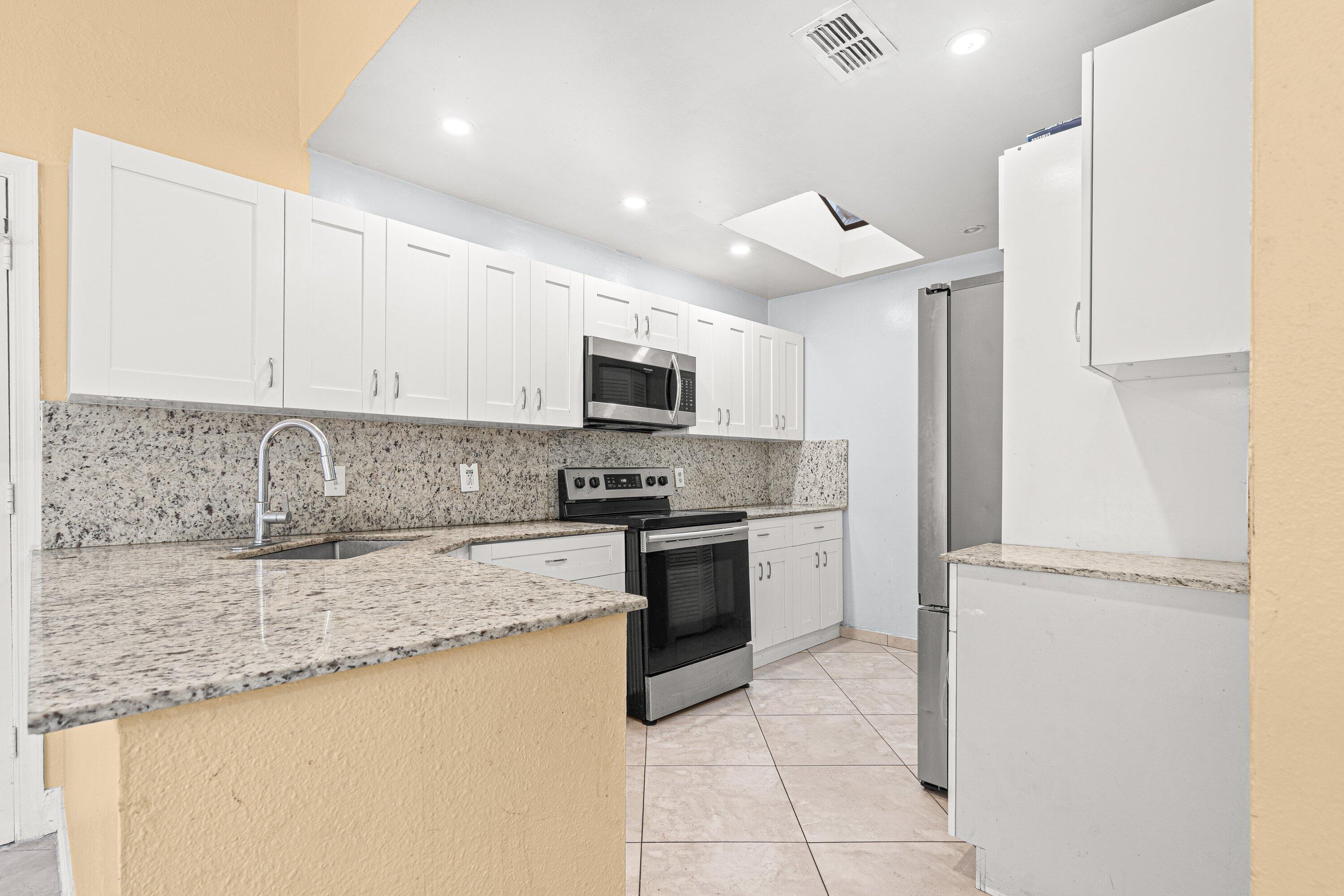 4134 Northwest 2nd Lane Delray Beach, FL 33445 - Photo 9 of 28 a kitchen with kitchen island granite countertop a stove sink and microwave