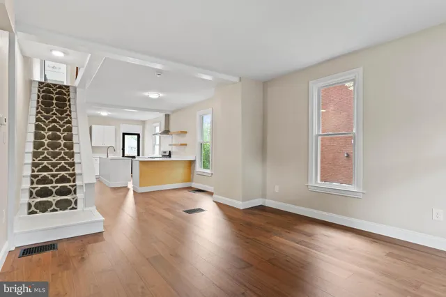 a view of an empty room with wooden floor and window
