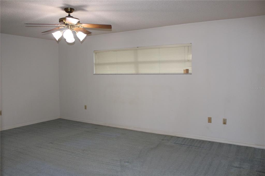 1638 Lamplighter Way Orlando, FL 32818 - Photo 13 of 25 an empty room with a chandelier fan and windows