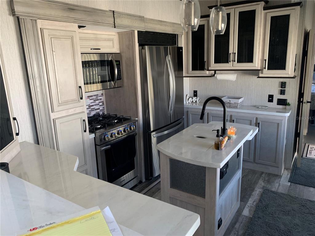 15991 Northeast 243rd Place Road, Unit 143 Fort McCoy, FL 32134 - Photo 14 of 35 a kitchen with stainless steel appliances a stove refrigerator sink and cabinets