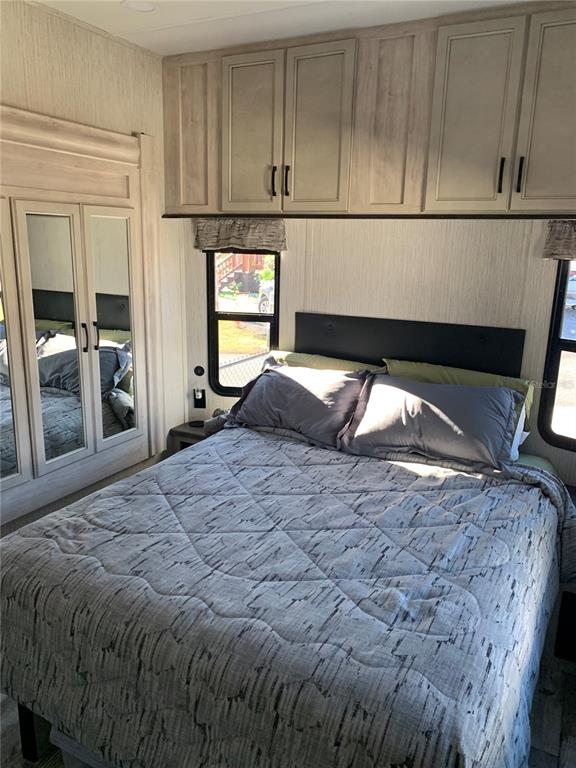 15991 Northeast 243rd Place Road, Unit 143 Fort McCoy, FL 32134 - Photo 17 of 35 a bedroom with a bed and a mirror