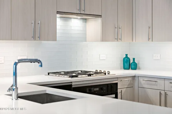 a kitchen with stainless steel appliances kitchen island granite countertop a stove a sink and white cabinets