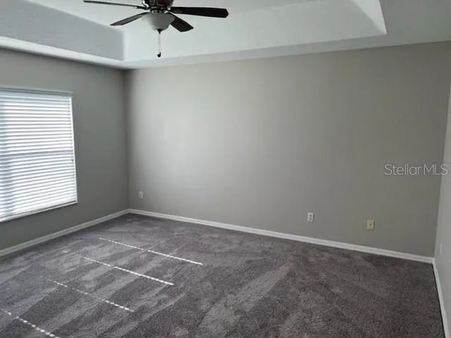 an empty room with a ceiling fan and window
