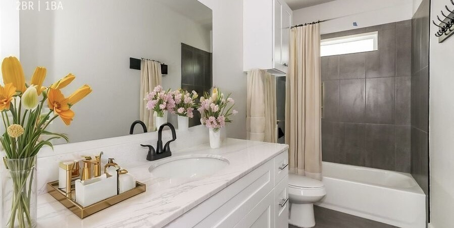a bathroom with a granite countertop sink a toilet and bathtub