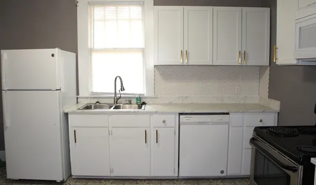 a kitchen with white cabinets and white appliances