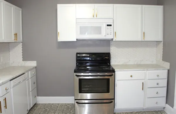 a kitchen with granite countertop white cabinets and white appliances