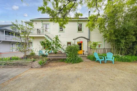 a view of a white house with a yard and plants