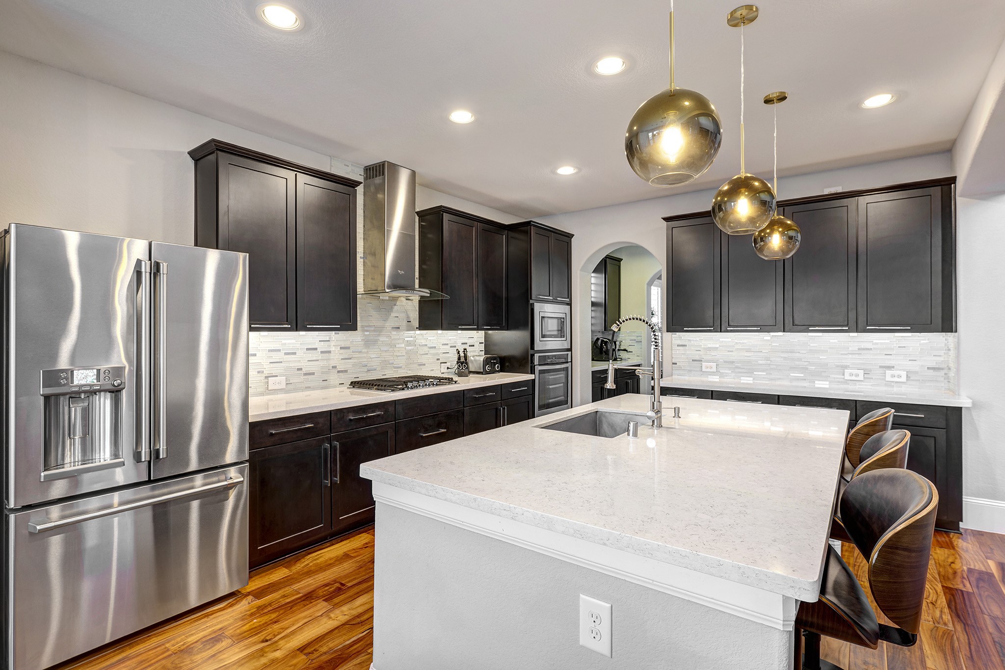 5002 Harvest Knoll Drive Spring, TX 77389 - Photo 14 of 48 Island Kitchen with espresso cabinets, glass tile backsplash and quartz countertops. The Island Breakfast Bar measures 8 feet. Perfect for entertaining or feeding the kids.