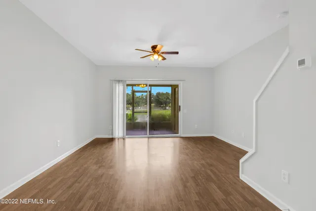 an empty room with wooden floor and glass door
