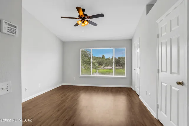 an empty room with wooden floor and windows