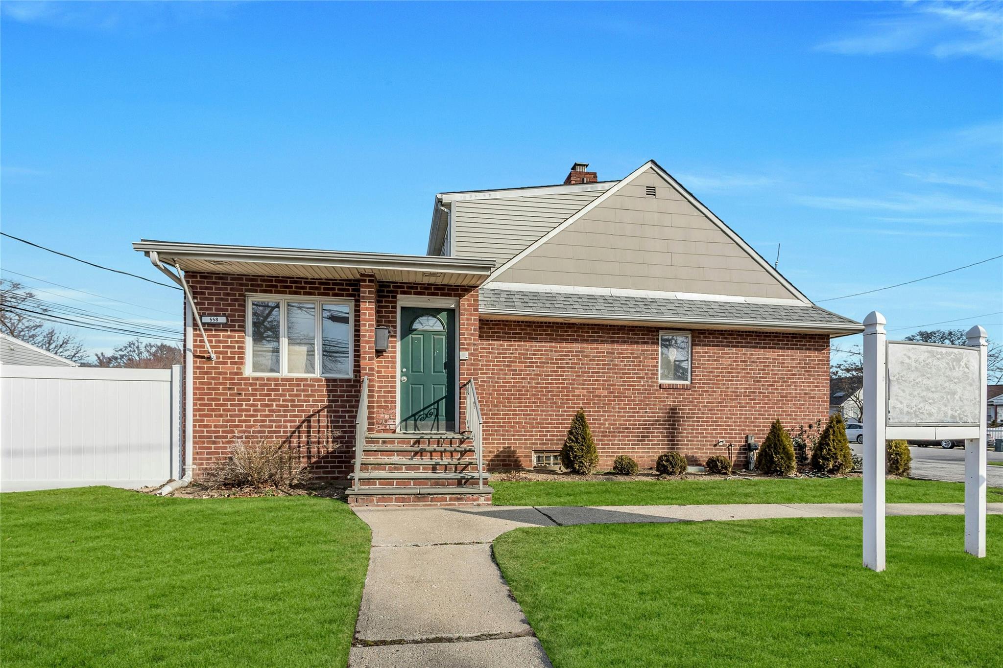 558 Old Country Road Plainview, NY 11803 - Photo 1 of 1 View of front of home featuring a front lawn, fence, a shingled roof, brick siding, and a chimney