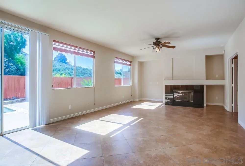5163 Riverview Court Fallbrook, CA 92028 - Photo 7 of 75 an empty room with windows fireplace and a kitchen view