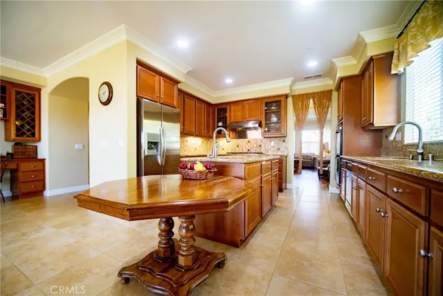 a large kitchen with kitchen island a large counter top space a sink a refrigerator and furniture