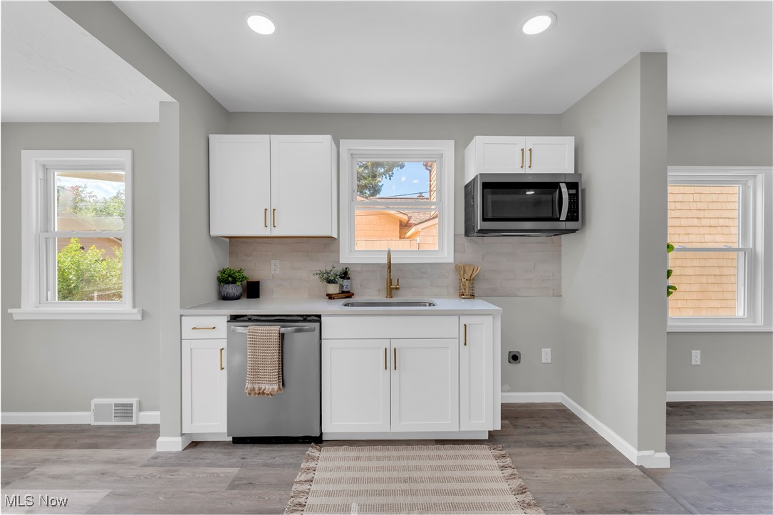 4124 Bayard Road Cleveland, OH 44121 - Photo 14 of 35 Kitchen with white cabinets, decorative backsplash, appliances with stainless steel finishes, recessed lighting, and light wood-style flooring