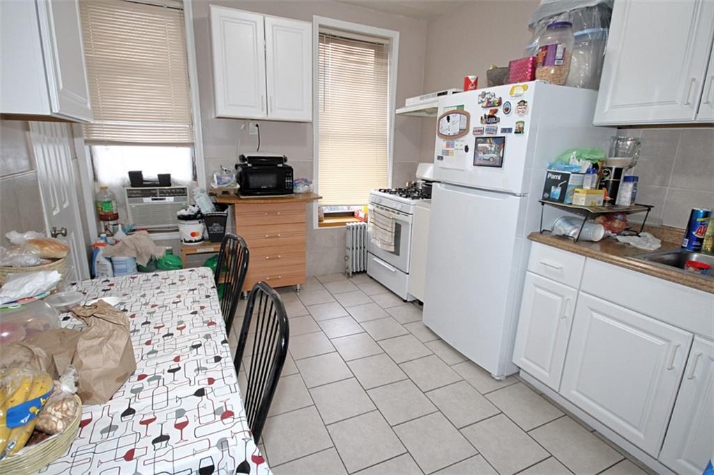 6018 4th Avenue Brooklyn, NY 11220 - Photo 4 of 15 a kitchen with a refrigerator and white cabinets