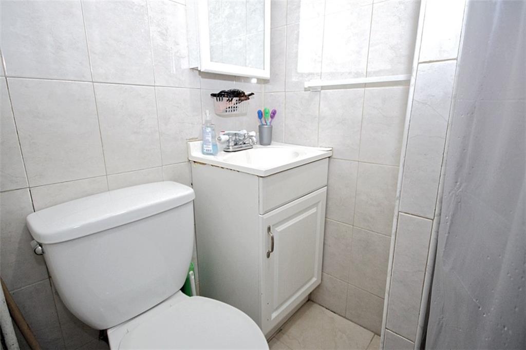 6018 4th Avenue Brooklyn, NY 11220 - Photo 8 of 15 a white toilet sitting next to a bathroom sink