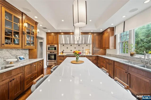 a view of a kitchen with kitchen island granite countertop a large counter top stainless steel appliances and windows