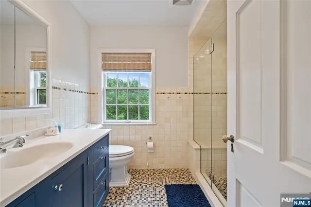 a bathroom with a sink a toilet a window and shower