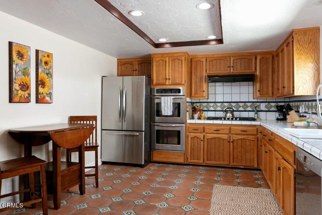 5000 Dolphin Way Oxnard, CA 93035 - Photo 36 of 56 a kitchen with stainless steel appliances granite countertop a refrigerator a sink dishwasher a stove top oven a kitchen island and chairs with wooden floor