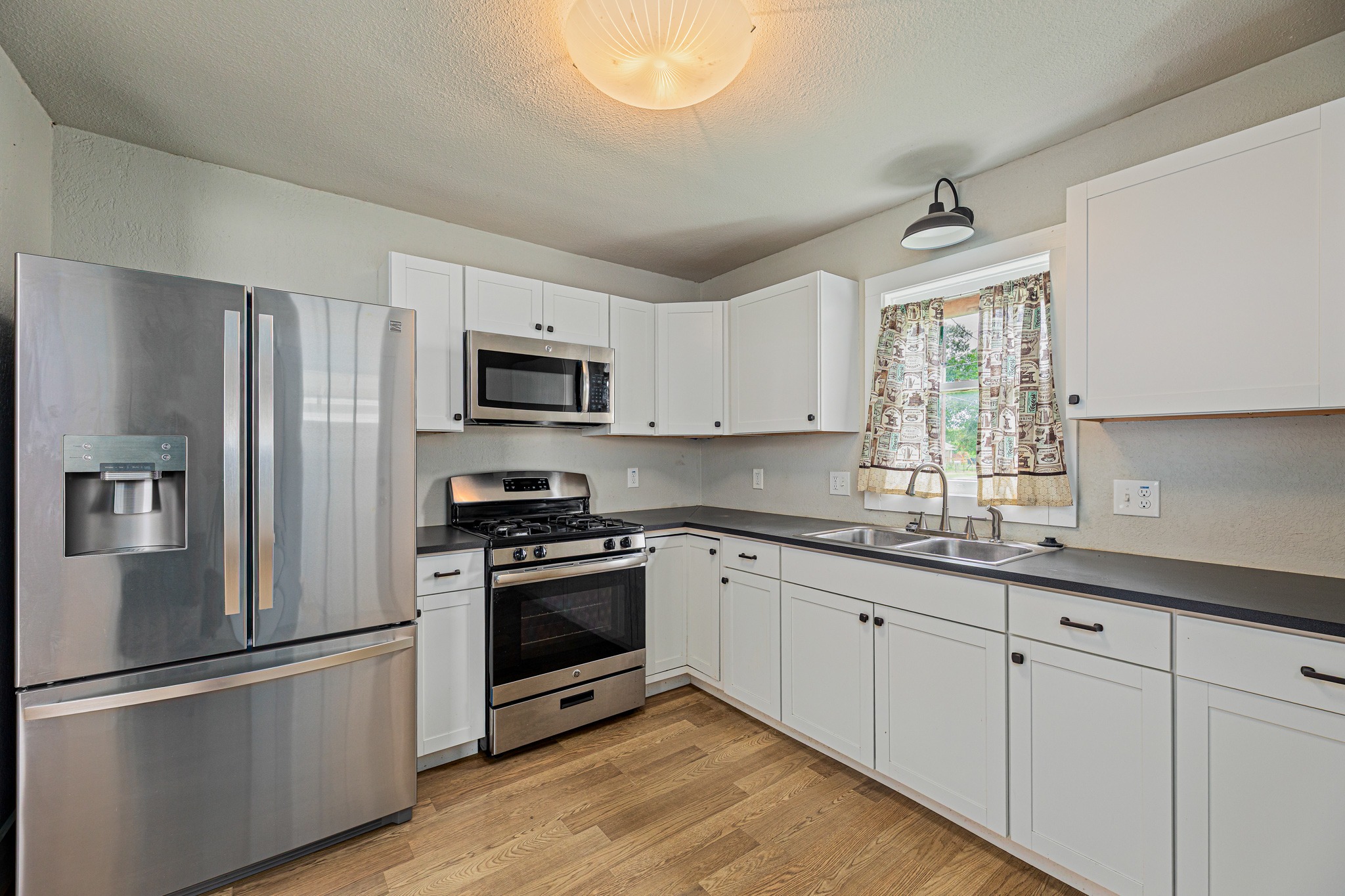 322 Blanco Avenue Luling, TX 78648 - Photo 8 of 20 Modern kitchen with white shaker cabinets and sleek stainless steel appliances.