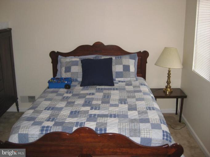 4950 Columbia Road, Unit 3 21 Columbia, MD 21044 - Photo 3 of 9 a large bed sitting in a bedroom next to a window with lamp on dresser