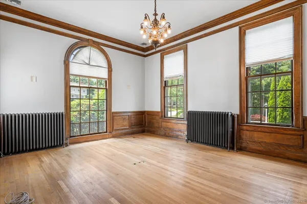 a view of an empty room with wooden floor fireplace and a window