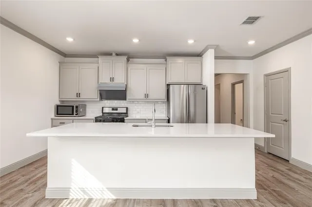 a view of kitchen with stainless steel appliances granite countertop cabinets and wooden floor