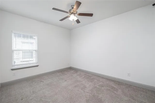 an empty room with a window and a ceiling fan