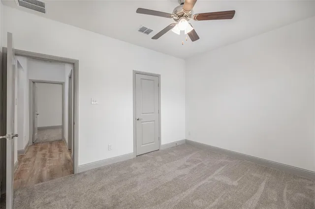 an empty room with closet and a chandelier fan