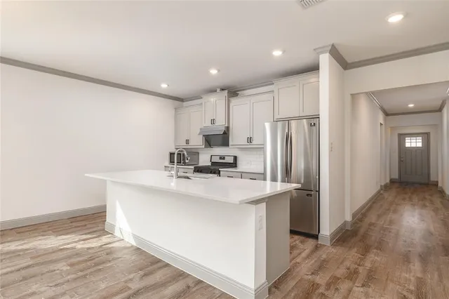 a kitchen with kitchen island a sink stainless steel appliances and cabinets