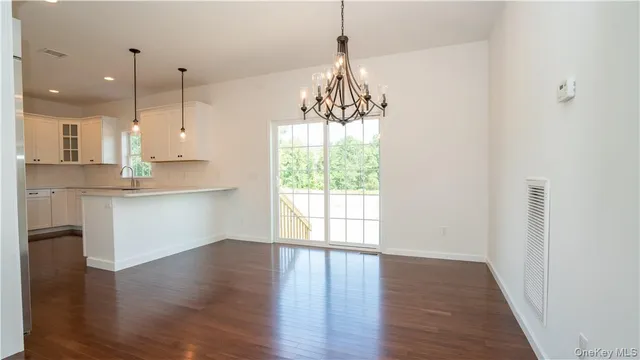 a kitchen with stainless steel appliances granite countertop a refrigerator a sink dishwasher a stove and white countertops with wooden floor